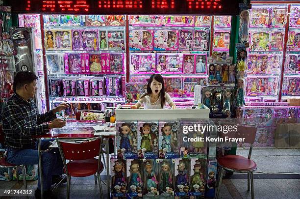 Chinese trader yawns as she waits for customers at her stall selling wholesale dolls at the Yiwu International Trade City on September 24, 2015 in...