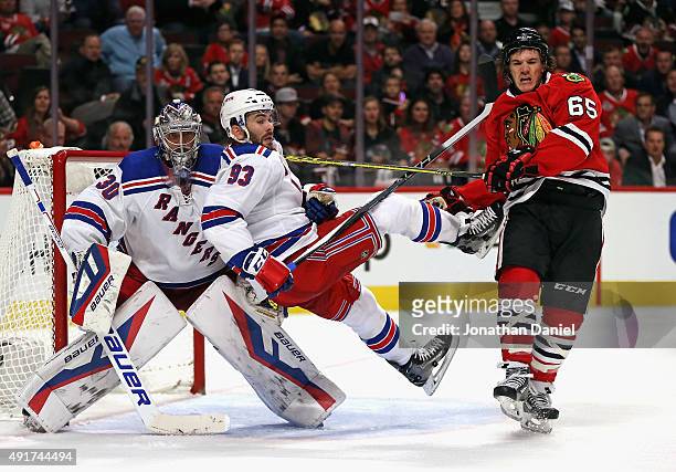 Andrew Shaw of the Chicago Blackhawks knocks Keith Yandle of the New York Rangers to the ice in front of Henrik Lindqvist at the United Center on...