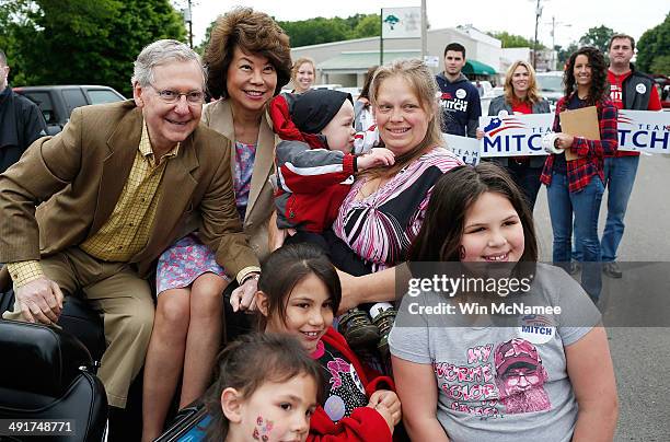 Senate Minority Leader Sen. Mitch McConnell poses for a photo while riding in the Fountain Run BBQ Festival parade with his wife Elaine Chao while...