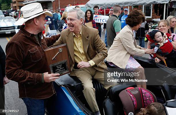 Senate Minority Leader Sen. Mitch McConnell greets voters while riding in the Fountain Run BBQ Festival parade with his wife Elaine Chao while...