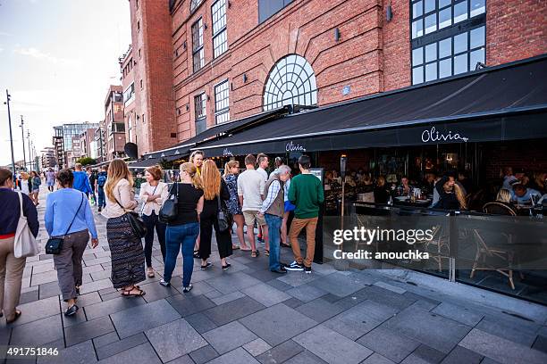 people waiting in line at the restaurant entrance - restaurant queue stock pictures, royalty-free photos & images