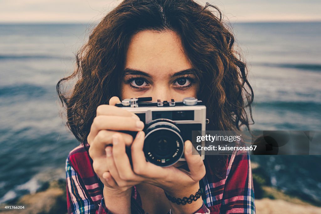 Girl taking a photo at sea with a film camera
