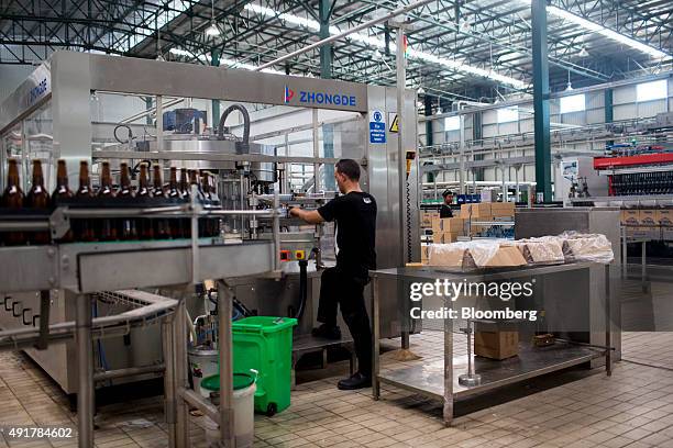 An employee adjusts a labeling machine on the bottling line at the Myanmar Carlsberg Co. Plant in Nyaung Inn Village, Bago, Myanmar, on Wednesday,...