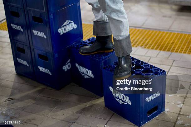 An employee stands on crates branded with the Yoma Beer logo on the bottling line at the Myanmar Carlsberg Co. Plant in Nyaung Inn Village, Bago,...