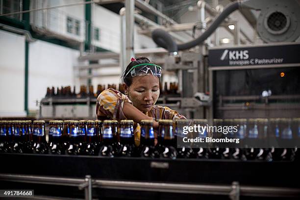 An employee checks bottles of Yoma Beer during quality control on the bottling line at the Myanmar Carlsberg Co. Plant in Nyaung Inn Village, Bago,...