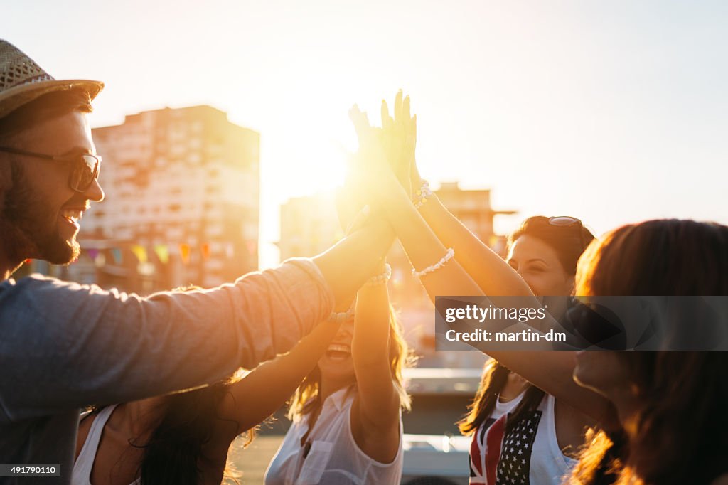 Happy friends at the rooftop doing high five