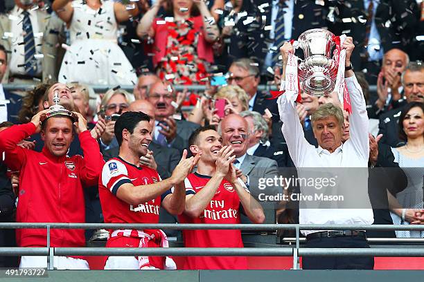 Arsene Wenger manager of Arsenal lifts the trophy in celebration alongside Lukas Podolski , Mikel Arteta and Thomas Vermaelen after the FA Cup with...