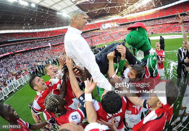 Thje Arsenal squad throw manager Arsene Wenger in the air after the FA Cup Final between Arsenal and Hull City at Wembley Stadium on May 17, 2014 in...