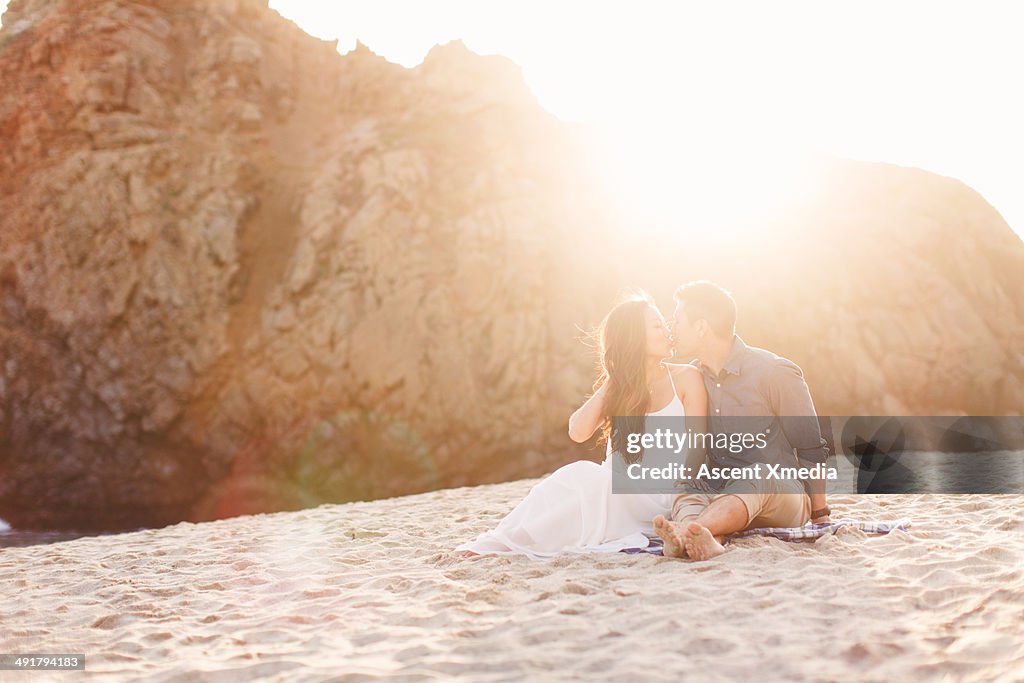 Asian couple exchange kiss on beach, sunset