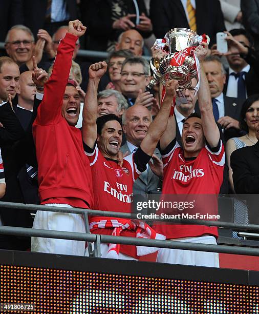 Lukas Podolski, Mikel Arteta and Thomas Vermaelen lift the FA Cup after the FA Cup Final between Arsenal and Hull City at Wembley Stadium on May 17,...