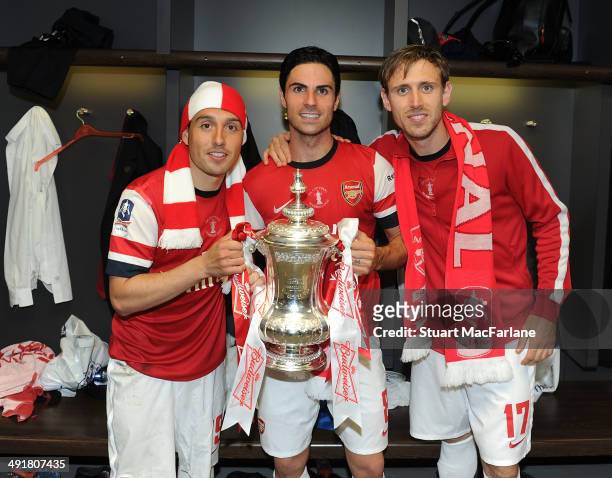 Santi Cazorla, Mikel Arteta and Nacho Monreal celebrate in the changing room after winning the FA Cup Final against Hull City at Wembley Stadium on...