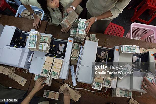 Employees count money after it has been deposited at the KBZ Bank main office on October 8, 2015 in Yangon, Burma. In Burma, the most widely...