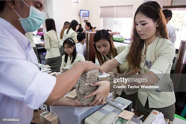 Bank employees handle kyat at the KBZ Bank main office on October 8, 2015 in Yangon, Burma. In Burma, the most widely deposited bank note is worth...