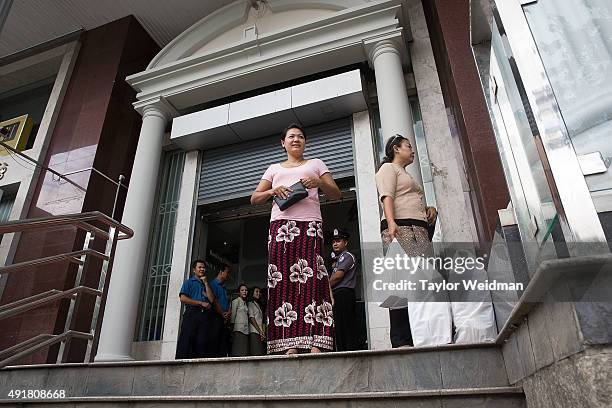 After a withdrawal, a customer waits for her ride next to bags full of kyat at the KBZ Bank main office on October 8, 2015 in Yangon, Burma. In...