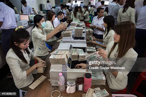 Employees count money after it has been deposited at the KBZ Bank main office on October 8, 2015 in Yangon, Burma. In Burma, the most widely...