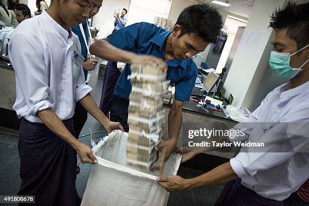Bank employees pack a bag full of kyat after a withdrawal at the KBZ Bank main office on October 8, 2015 in Yangon, Burma. In Burma, the most widely...