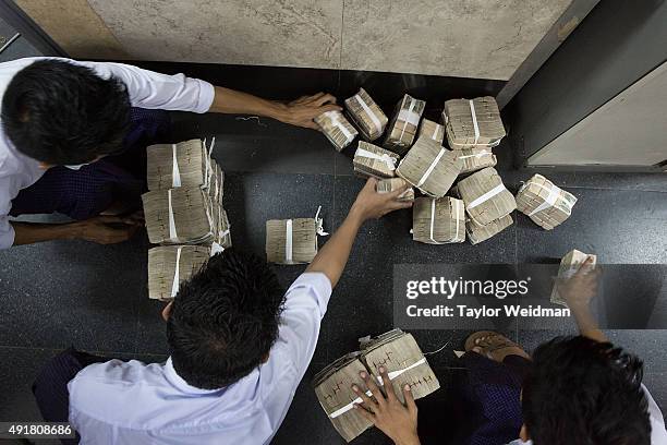 Employees stack money which a customer is withdrawing at the KBZ Bank main office on October 8, 2015 in Yangon, Burma. In Burma, the most widely...
