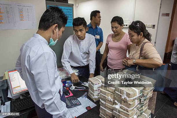 Customers make a withdrawal of roughly $35,000 at the KBZ Bank main office on October 8, 2015 in Yangon, Burma. In Burma, the most widely deposited...