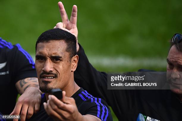 New Zealand's flanker Jerome Kaino makes a selfie as New Zealand head coach Steve Hansen gestures behind him at the end of the captain's run training...