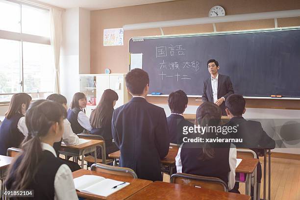 japanese student stand answering a question to his teacher - japan 12 years girl stock pictures, royalty-free photos & images