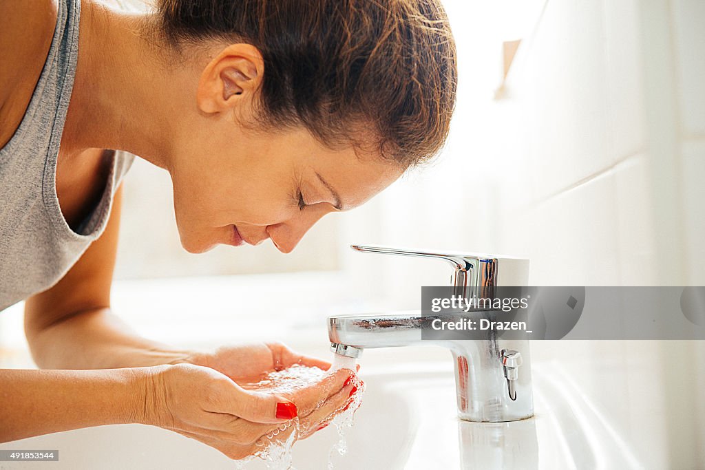 Young cheerful woman having morning hygiene in bathroom