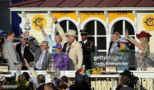 Trainer Art Sherman raises a copy of the Woodlawn Vase while standing with jockey Victor Espinoza and co-owner Steven Coburn in the Winner's Circle...