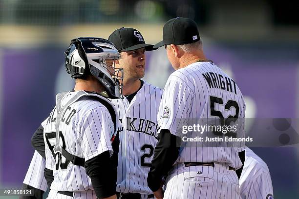 Pitching coach Jim Wright of the Colorado Rockies talks with starting pitcher Jordan Lyles and catcher Jordan Pacheco during the first inning against...