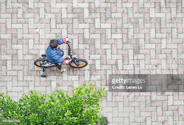 boy riding bicycle alone in courtyard. - steinplatte stock-fotos und bilder