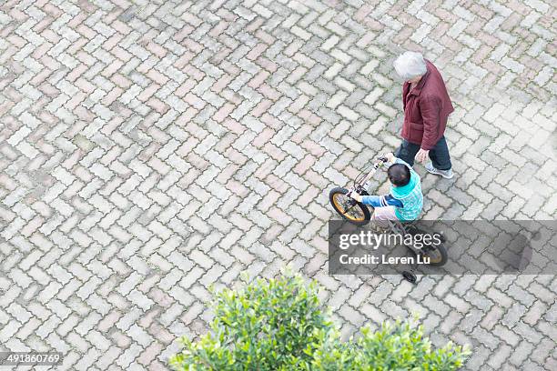 boy riding bicycle next to grandmother. - fahrrad fahren großeltern mit kind stock-fotos und bilder