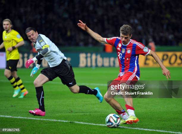 Thomas Mueller of FC Bayern Muenchen pus the ball past Roman Weidenfeller of Dortmund as he scores the second goal during the DFB Pokal between FC...