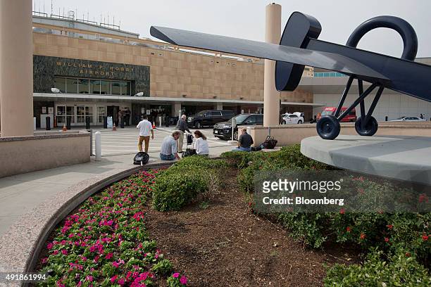 Travelers sit outside of the William P. Hobby Airport in Houston, Texas, U.S., on Thursday, Oct. 8, 2015. Starting Oct. 15, Southwest will embark on...