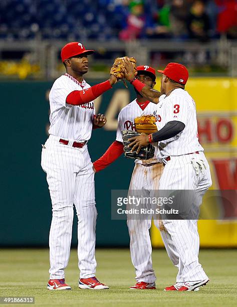 Outfielders Domonic Brown, Tony Gwynn Jr. #19 and Marlon Byrd of the Philadelphia Phillies congratulate each other after defeating the Cincinnati...