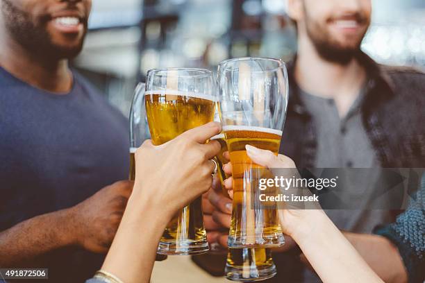 friends toasting with beer in a pub - hand-holding-pint stock pictures, royalty-free photos & images