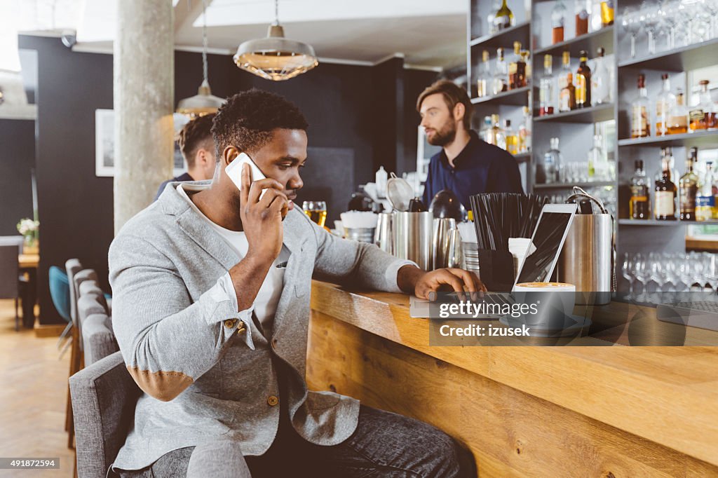 Afro american man using laptop in a pub