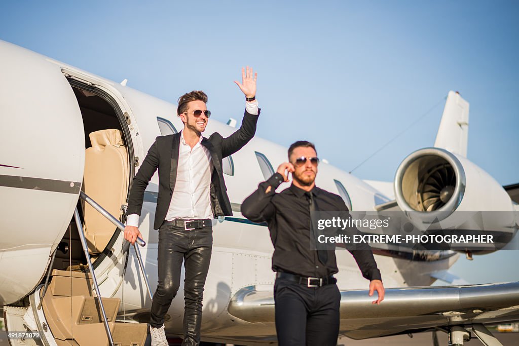 Celebrity and bodyguard leaving the jet airplane