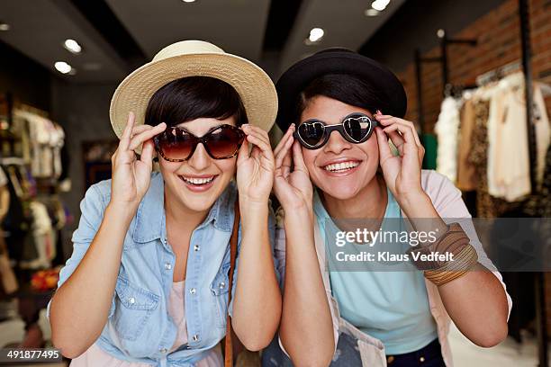 girlfriends trying on sunglasses and having fun - a woman wear hat and sunglasses stock pictures, royalty-free photos & images