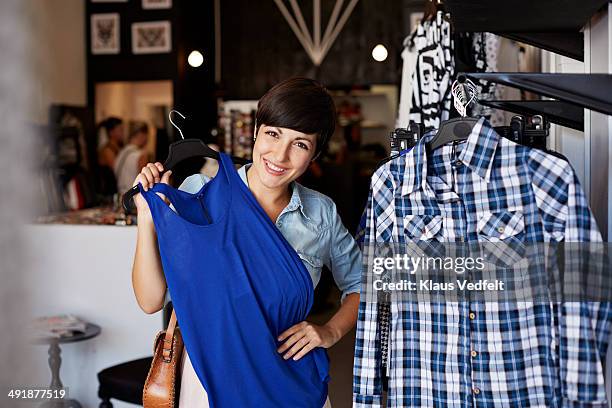 portrait of woman trying dress in fashion store - blue dress stock pictures, royalty-free photos & images