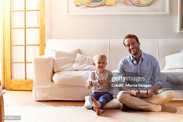 father and son playing video games - gambe incrociate foto e immagini stock