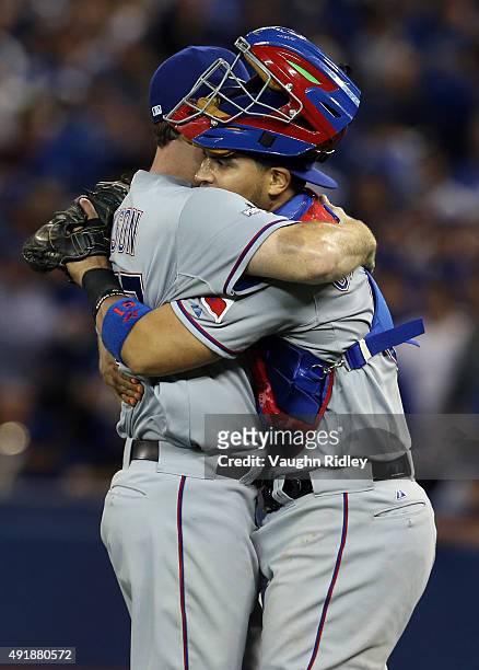 Sam Dyson of the Texas Rangers celebrates with his teammate Robinson Chirinos after defeating the Toronto Blue Jays after game one of the American...