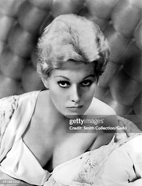 Kim Novak headshot, with a seductive expression, partially nude and draped in fabric, 1960.