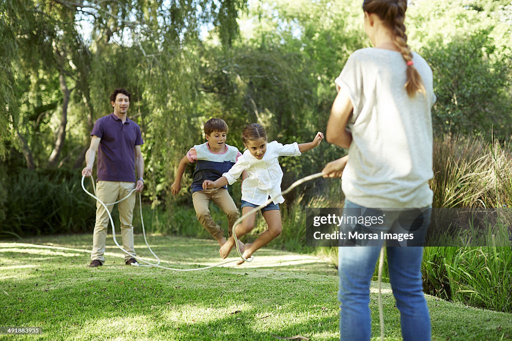 Family playing jump rope in park