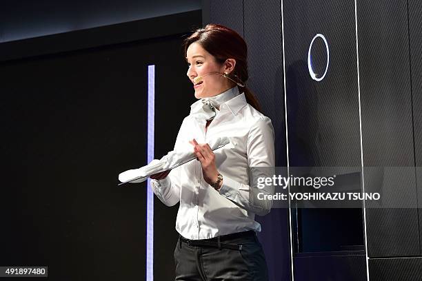 This photo taken on October 7, 2015 shows a model holding a folded shirt while demonstrating a prototype of an automatic laundry folding machine...