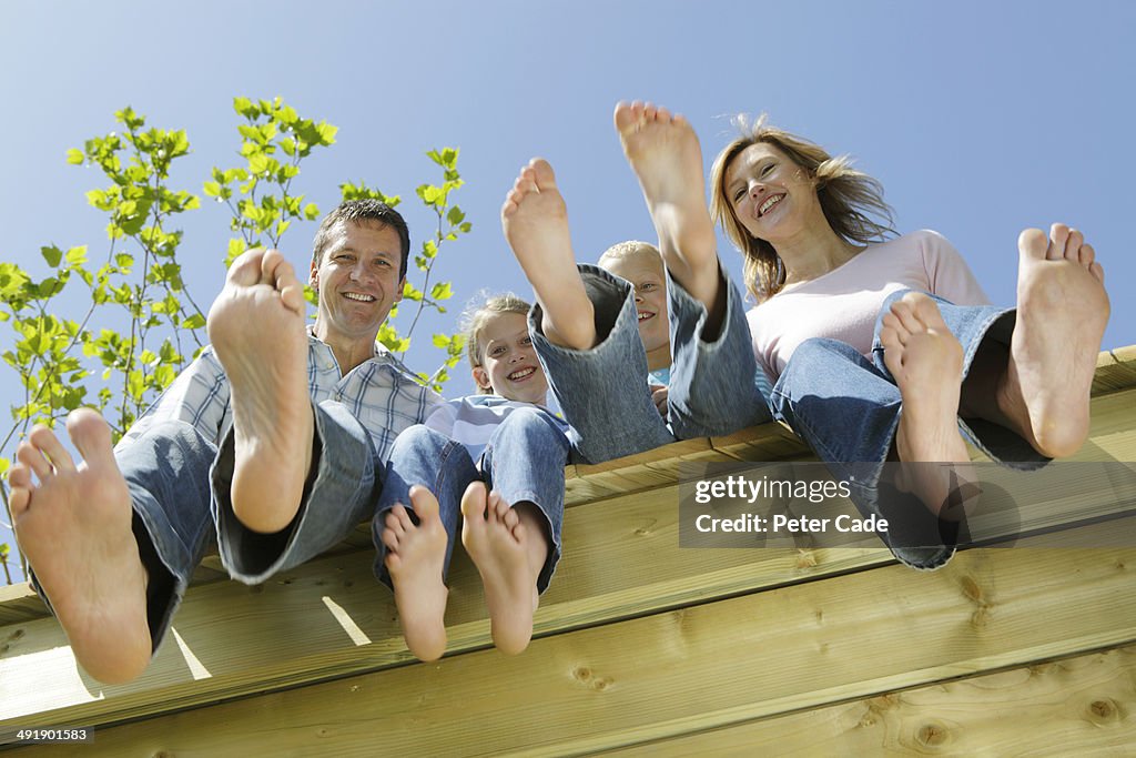 Family sitting on edge of decking, view from below