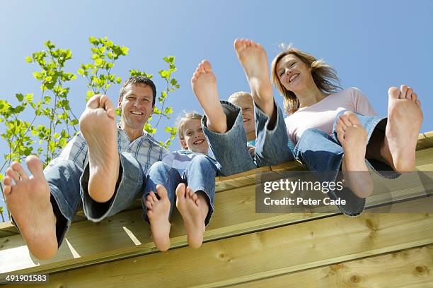 family sitting on edge of decking, view from below - soles pose stock pictures, royalty-free photos & images