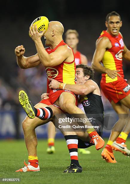 Gary Ablett of the Suns handballs whilst being tackled by Lenny Hayes of the Saints during the round nine AFL match between the St Kilda Saints and...