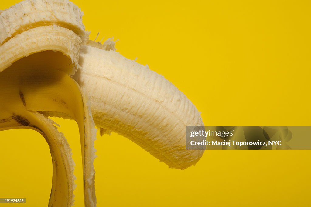 Peeled banana on yellow background