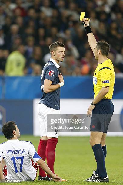 Morgan Schneiderlin of France receives a yellow card from referee Slavko Vincic of Slovenia during the international friendly match between France...