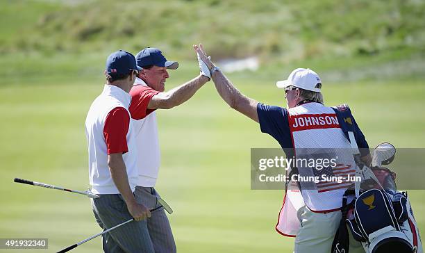 Phil Mickelson of the United States Team celebrates with Zach Johnson and Johnson's caddie Damon Green after holing a bunker shot on the 12th hole...