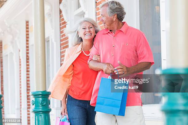 mature couple shopping, walking outside building - seniors shopping stock pictures, royalty-free photos & images