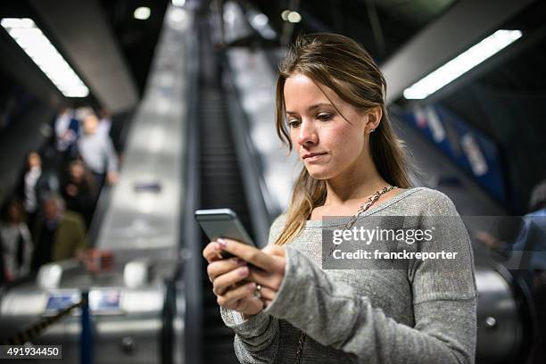 woman using a smartphone on the metro subway station - crowded underground london stock pictures, royalty-free photos & images